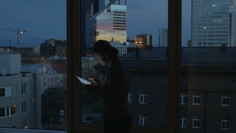 Woman-Typing-in-Tablet-by-the-Window