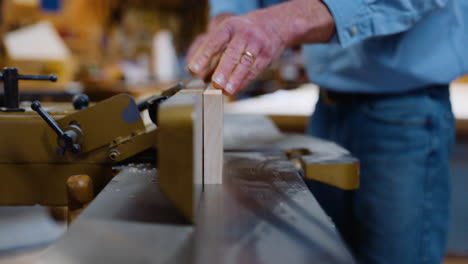 carpintero poniendo un trozo de madera a través de una cepilladora de madera