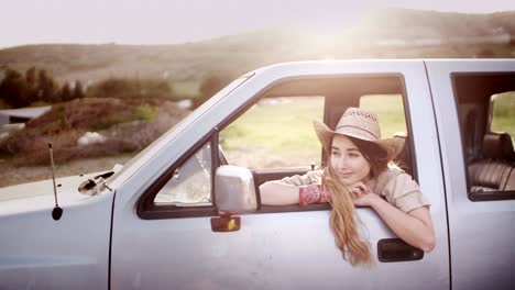 attractive country girl sitting in pick-up truck in a farm