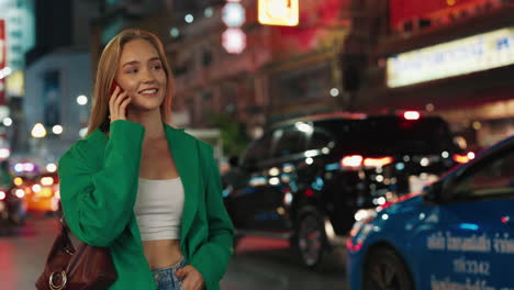 young woman talking on phone in a city at night