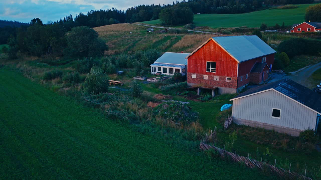 Luftfoto av et bærekraftig høstsmåbruk med en klassisk rød låve, opphøyde plantebed og uthus, innrammet av høstgrønt
