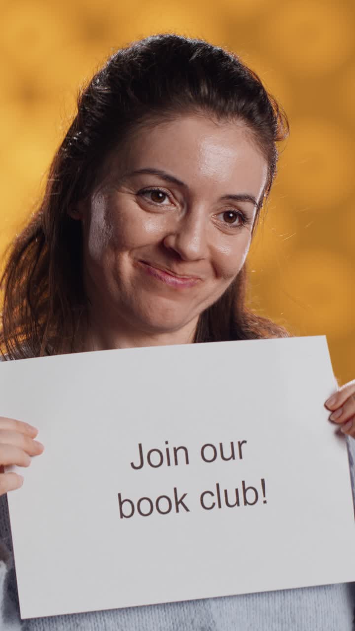 Smiling Woman Holding 'Join Our Book Club' Sign