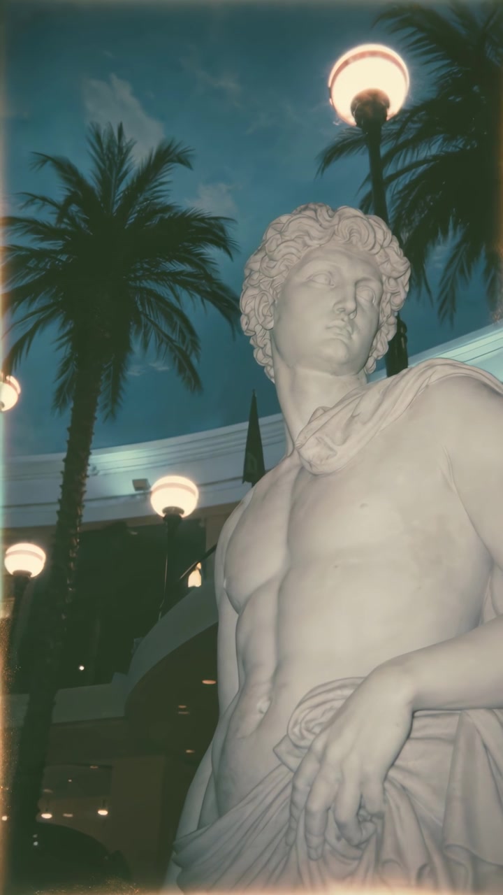 Statua classica di un uomo in un cortile tropicale di notte