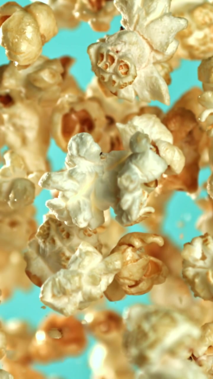 Golden Popcorn Falling in Slow Motion on Teal Background