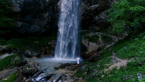 man with beard is doing waterfall-meditation under big waterfall