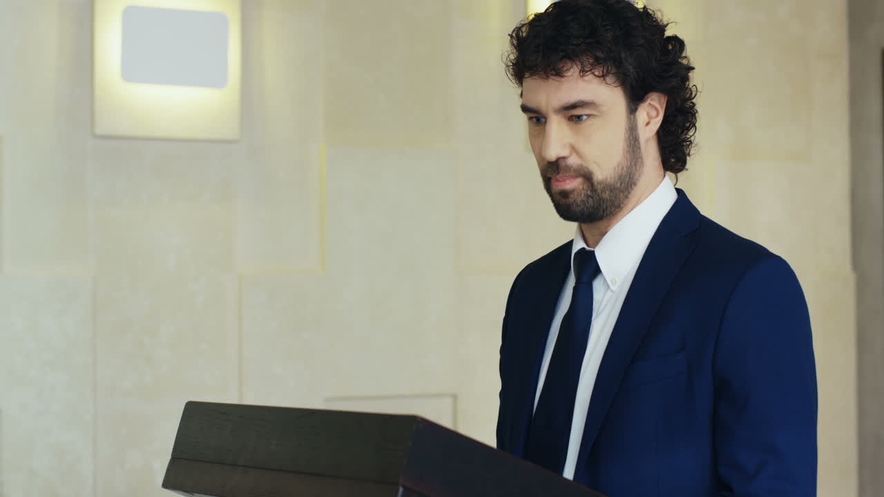 白人商人在会议台上发言,并在演讲中与大厅中的人互动