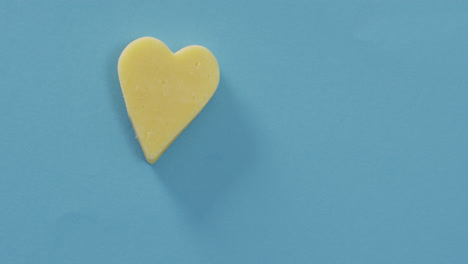 video of heart shape of cheese on blue background with copy space