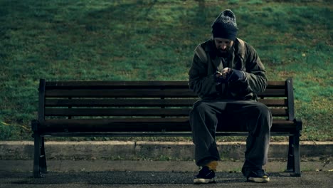 poor beggar sit on bench at night, counting his alms