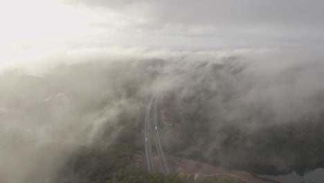 Drohnenaufnahmen-Von-Autobahnen-Und-Wohnsiedlungen-In-Norwegen-Mit-Etwas-Nebel-In-Der-Luft-Und-Sonne,-Die-Die-Wolken-Erhellt