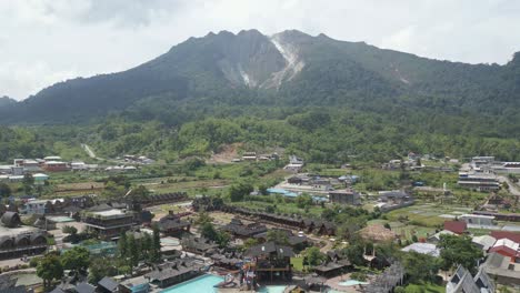 panaroma of mount sibayak, aerial drone fly over the pariban hot springs residential valley at berastagi, north sumatera, indonesia