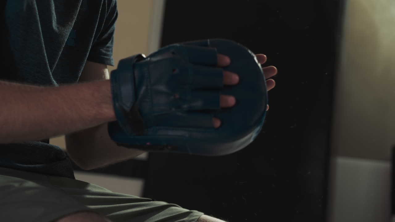 el instructor sostiene la almohadilla mientras el niño patea en el gimnasio en primer plano. el entrenador de artes marciales enseña al niño pequeño a golpear en el club deportivo en cámara lenta. pelea de kickboxing