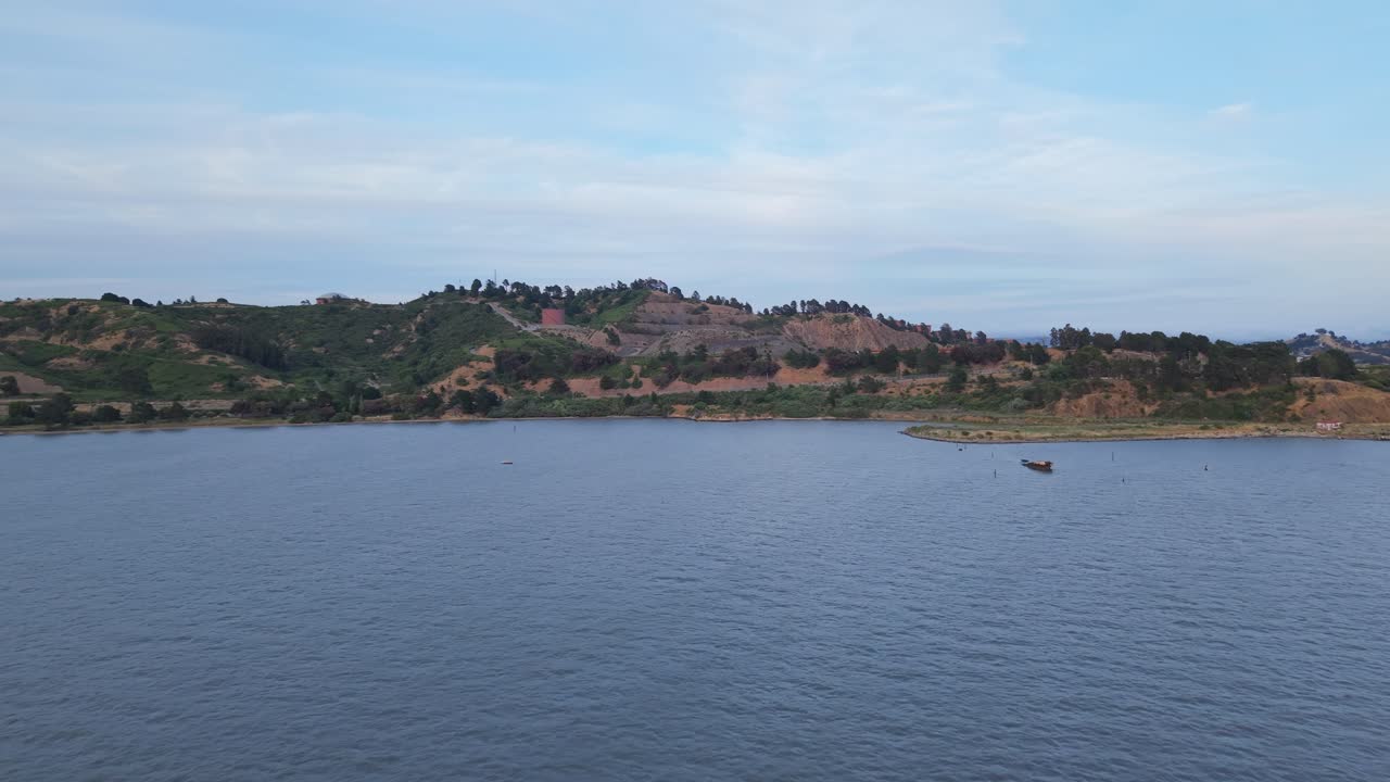 Aerial view of Point Molate Beach reveals peaceful waves meeting a quiet shoreline tucked beneath gentle hills.