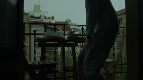 Woman-in-Pajamas-Alone-on-Balcony-sits-Sipping-Coffee-from-Mug-in-Pre-Dawn-Darkness-Blue-Hour-Early-Morning-Serenity-wide-shot