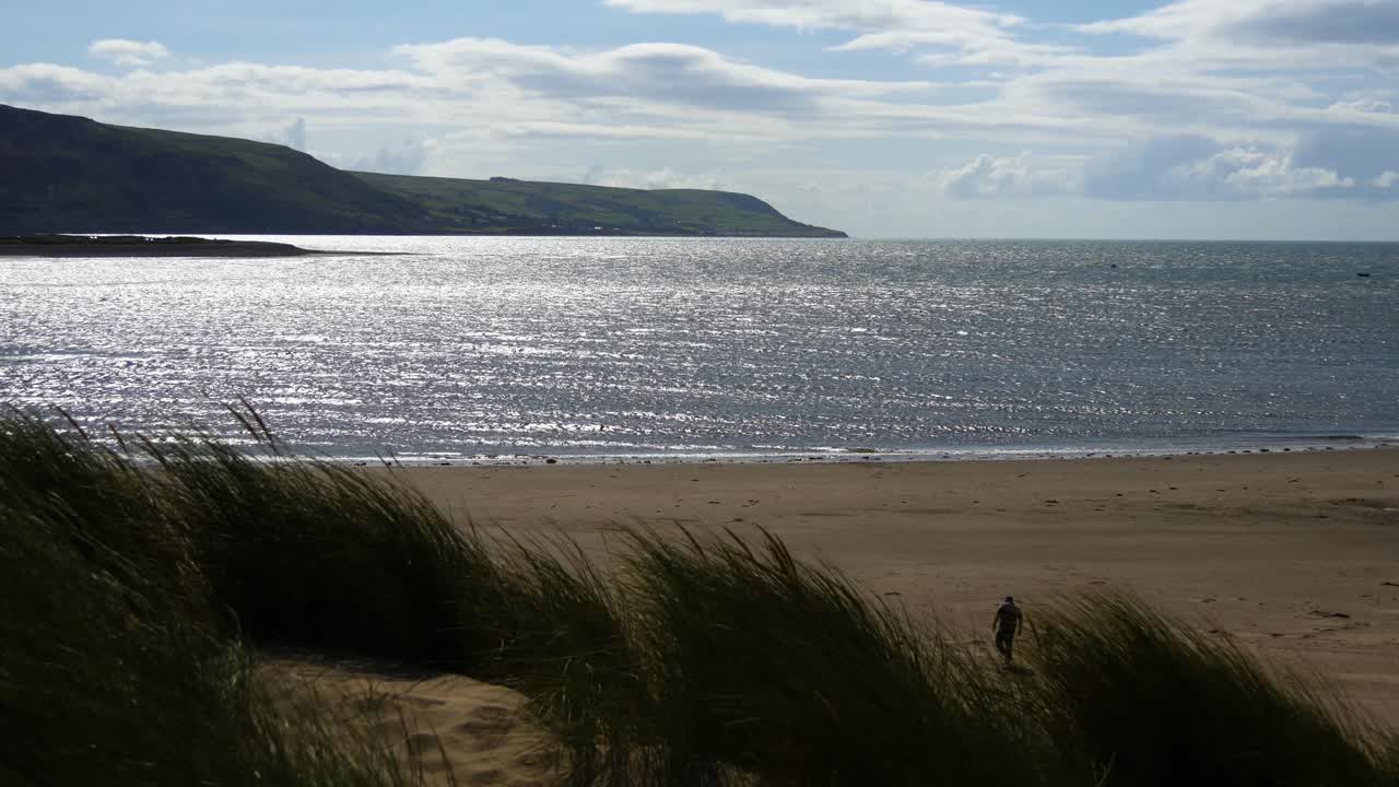 영국 웨일즈의 바머스, 모래언덕, 바다에서 해변을 향해 걸어가는 사람들 - 10초 버전