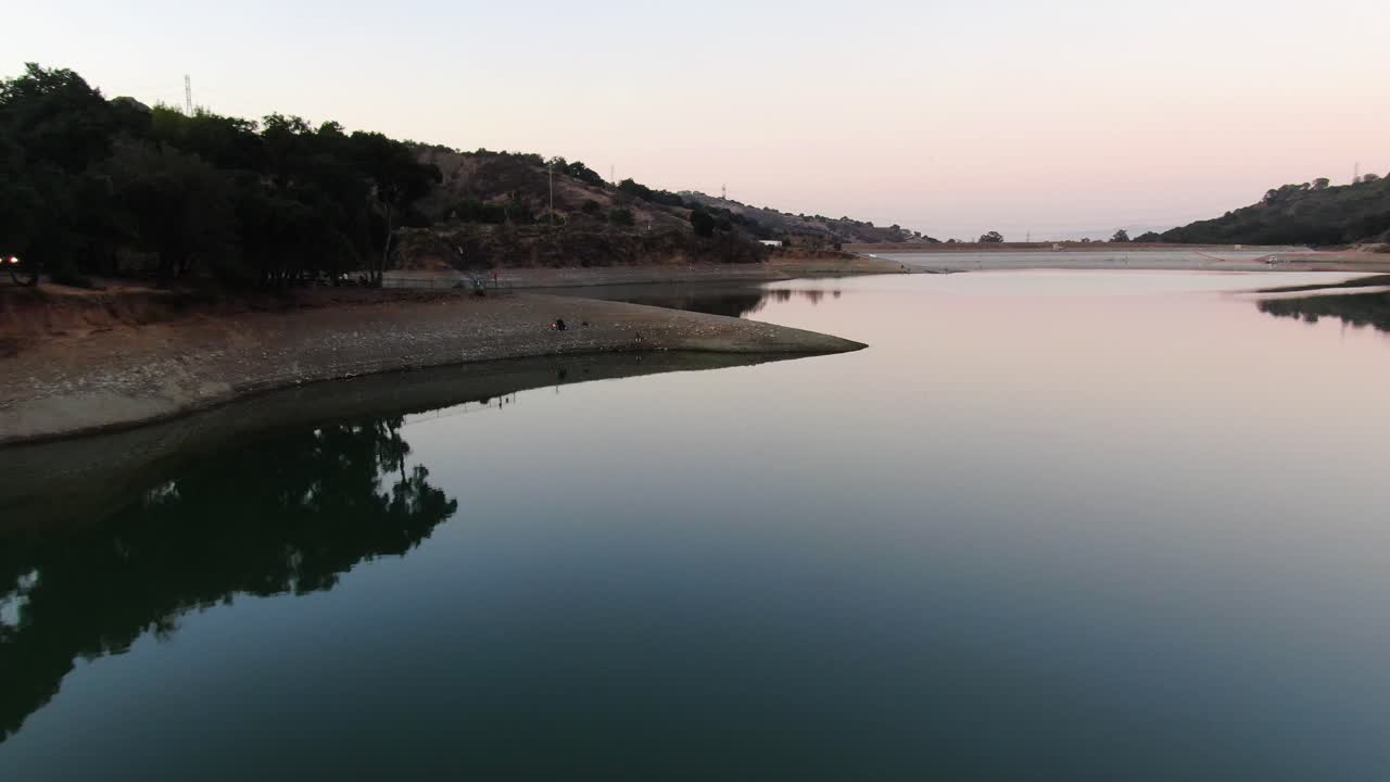 Drone shot over the lake's reflection, and shores at Stevens Creek Reservoir in Cupertino, California