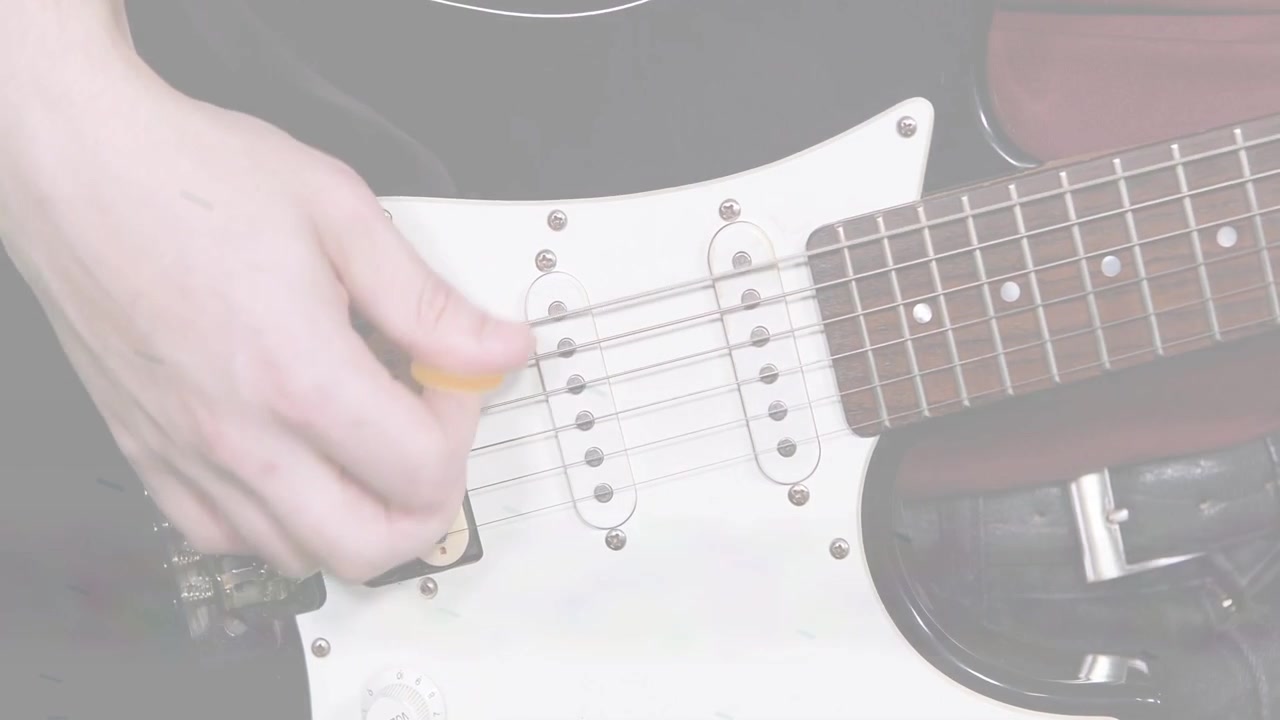 Gitaristin sağ eli, müzik için telleri çalmak üzere pena vuruşuna başlıyor, sarı pena pena koruyucuyu sıyırıyor.