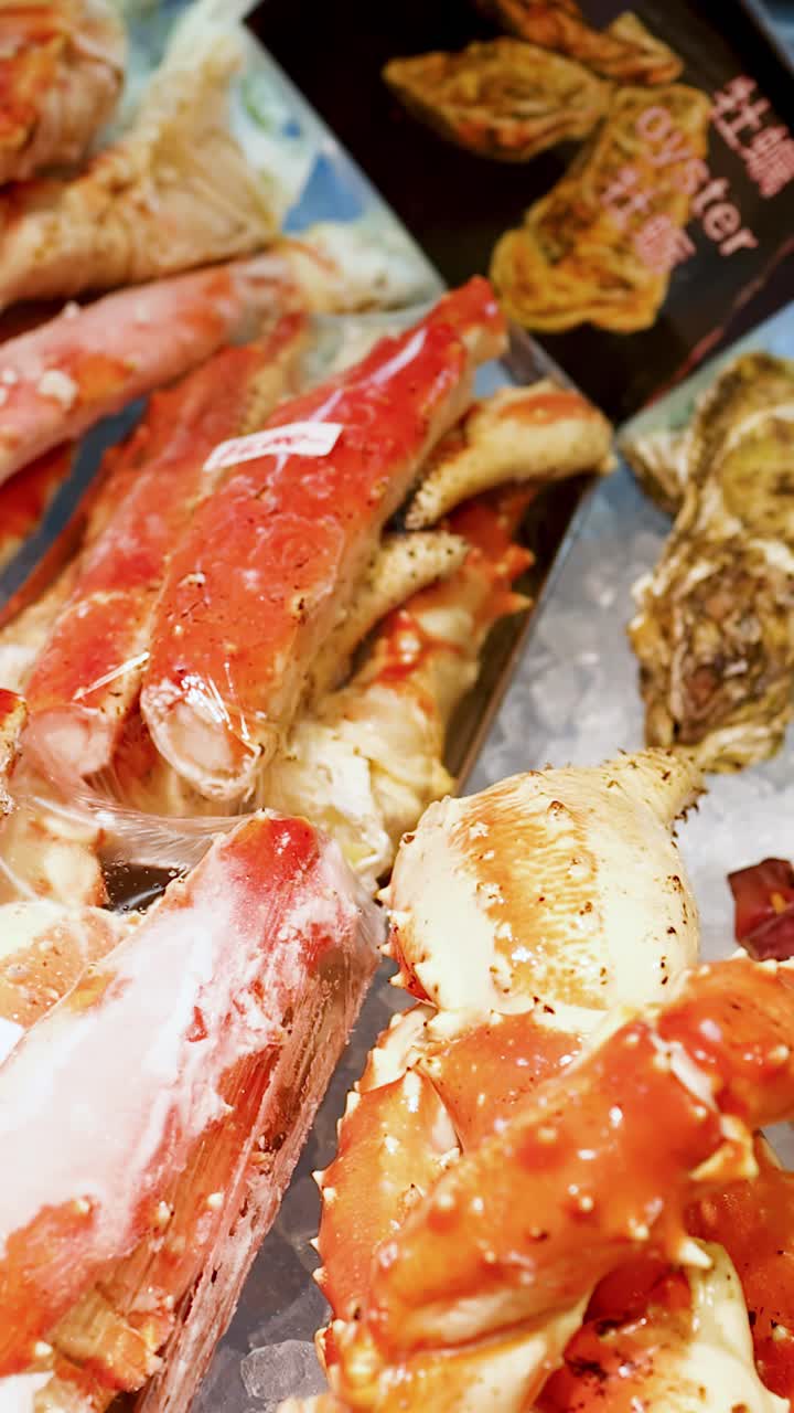 Close-up panning shot of king crab legs, scallops, and shrimp on ice in Osaka