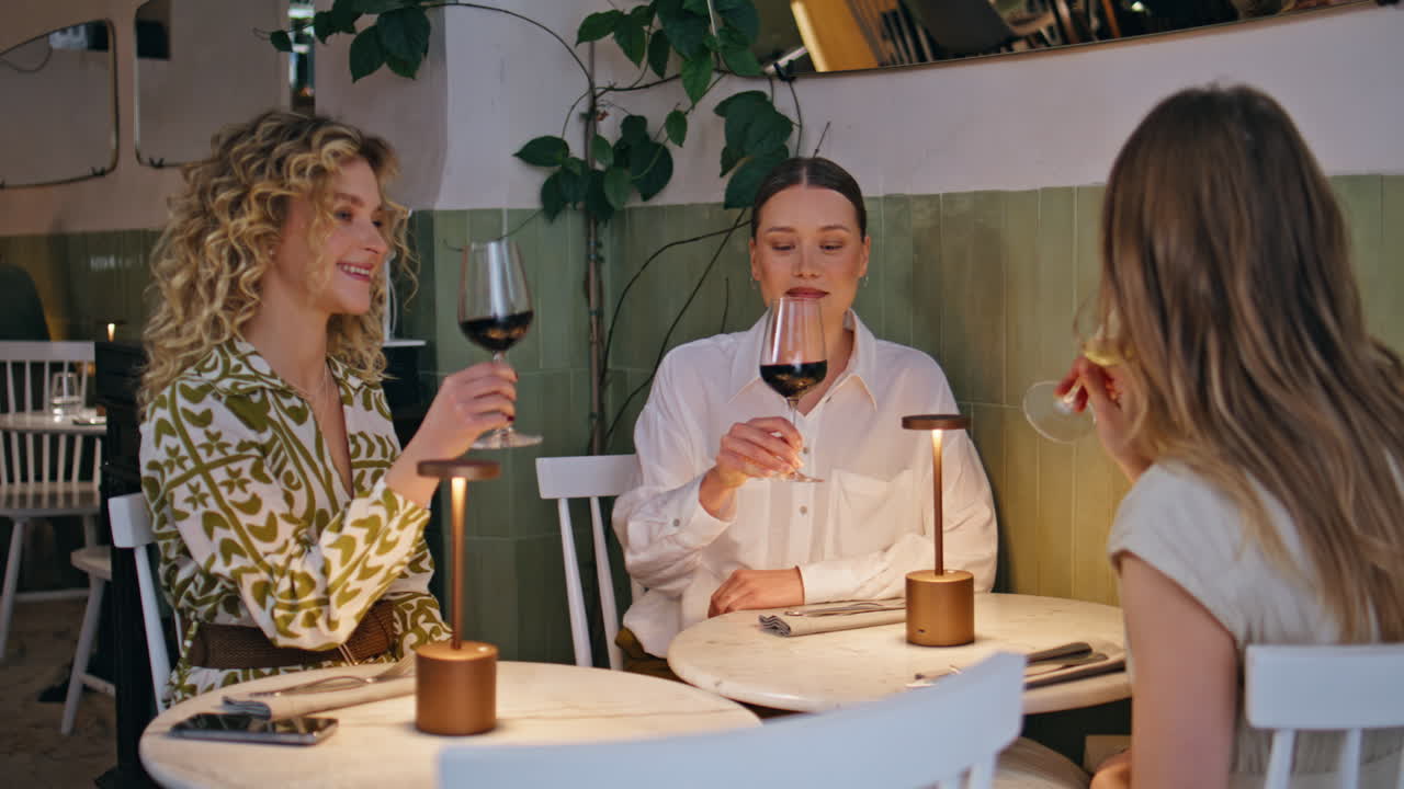 Three women toasting together with wine glasses at joyful gathering restaurant