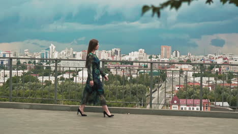 mujer bonita en vestido elegante camina a lo largo de la cubierta de observación