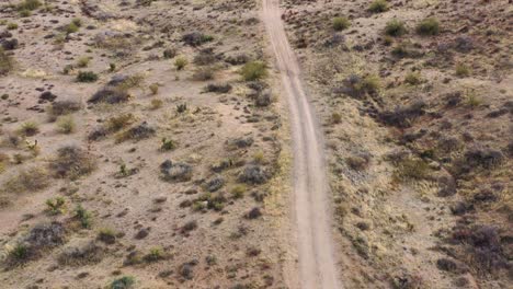 Aerial,-tilt-down-along-an-isolated-dirt-road-in-the-middle-of-the-Sonoran-Desert,-Scottsdale,-Arizona