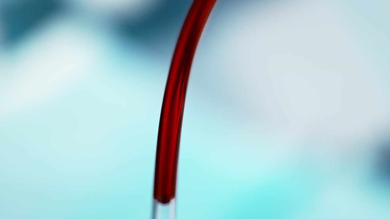transfusión de sangre a través de un tubo transparente en un fondo azul borroso del hospital, líquido rojo en macro y cámara lenta