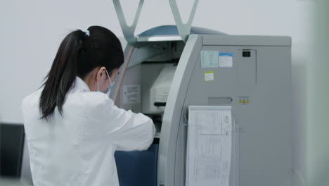 scientist wearing lab coat in a modern medical biological research. bioengineer in white coat handling test tubes, putting them inside advanced machine for analysis in cleanroom environmental facility