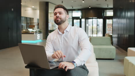 sad nervous businessman waiting for meeting conference with someone on laptop in modern office lobby