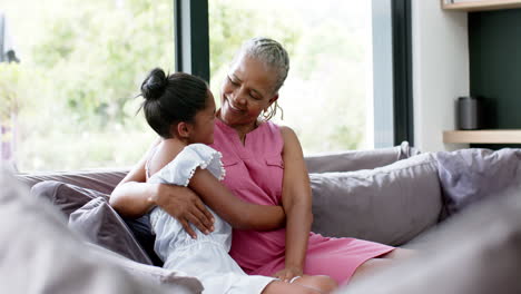 feliz nieta afroamericana y abuela abrazándose en el sofá, espacio de copia, cámara lenta