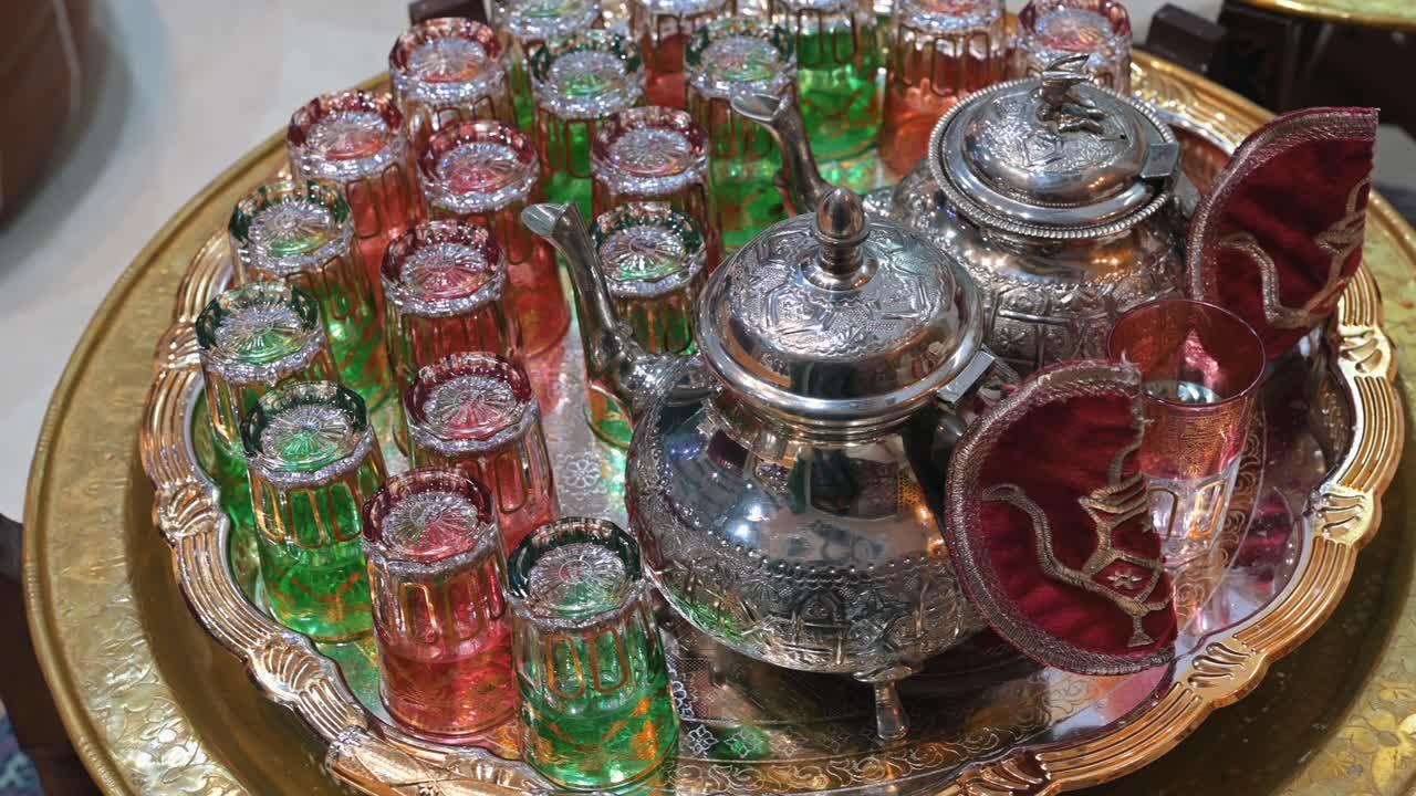 Traditional Moroccan tea set with a silver teapot, displayed on a decorative tray