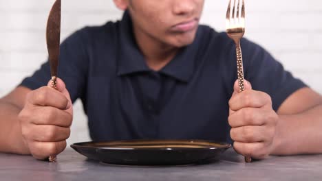 hand holding cutlery with empty plate on wooden table