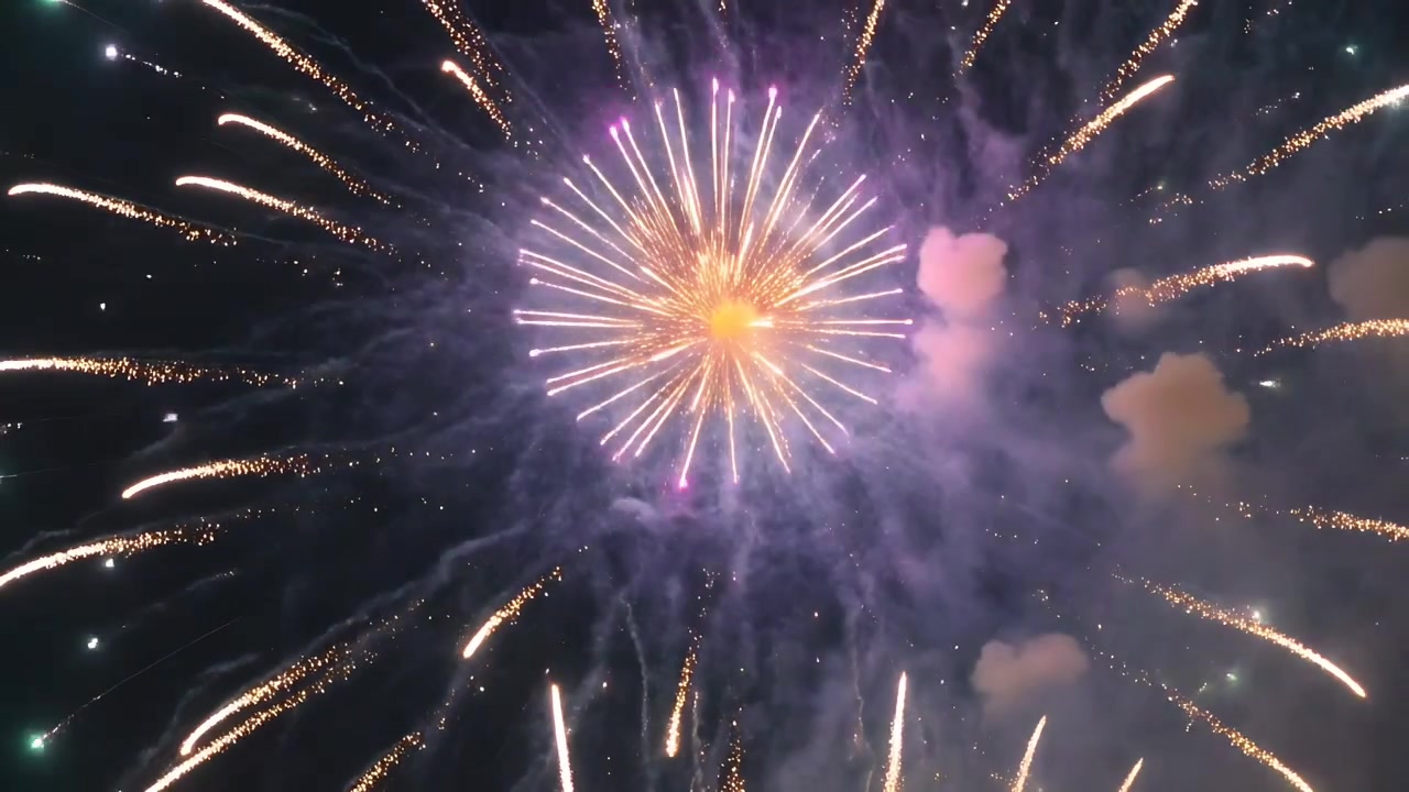 Igniting aerial shell making burst expanding overhead, with orange core and radial trails