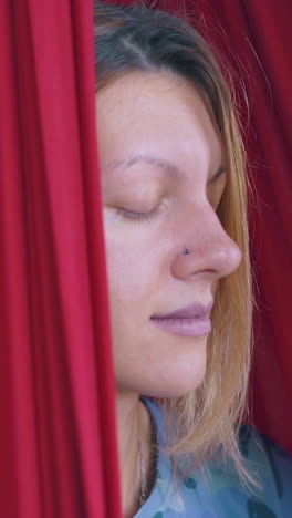 nice lady profile sitting with closed eyes and meditating in modern fly yoga hammock extreme close view