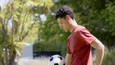 Hombre-Birracial-Enfocado-Practicando-Habilidades-Futbolísticas-En-Un-Jardín-Soleado,-Espacio-Para-Copiar,-Cámara-Lenta