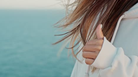 slow motion shot of girl moving fingers into her beautiful brown hair in front of sea