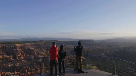 tourists on the overlook at bryce point during sunrise