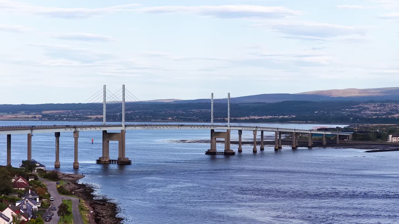 Wide daytime aerial pan reveals modern bridge, river, and surrounding landscape in clear weather