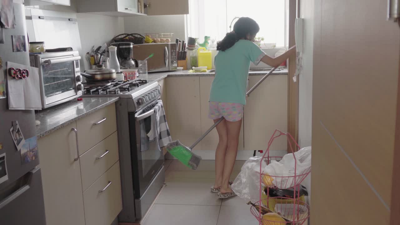 Woman Sweeping the Floor in a Modern Kitchen