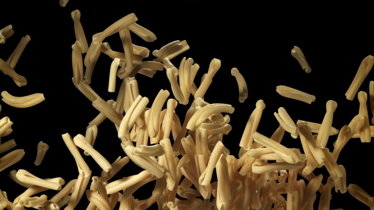 Pasta Casarecce Secca che Cade al Rallentatore su Sfondo Nero