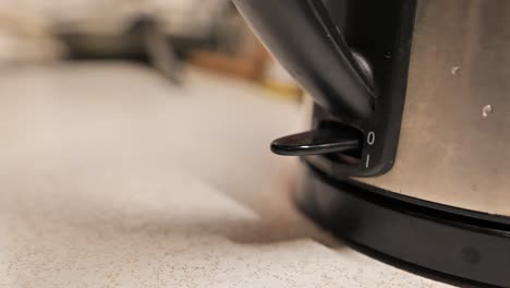 woman turns on an electric kettle by pressing a button - 4k.