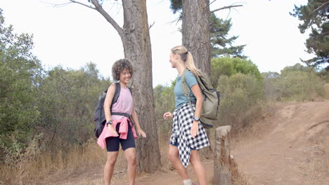 Young-biracial-woman-and-Caucasian-woman-chat-during-a-hike-in-nature