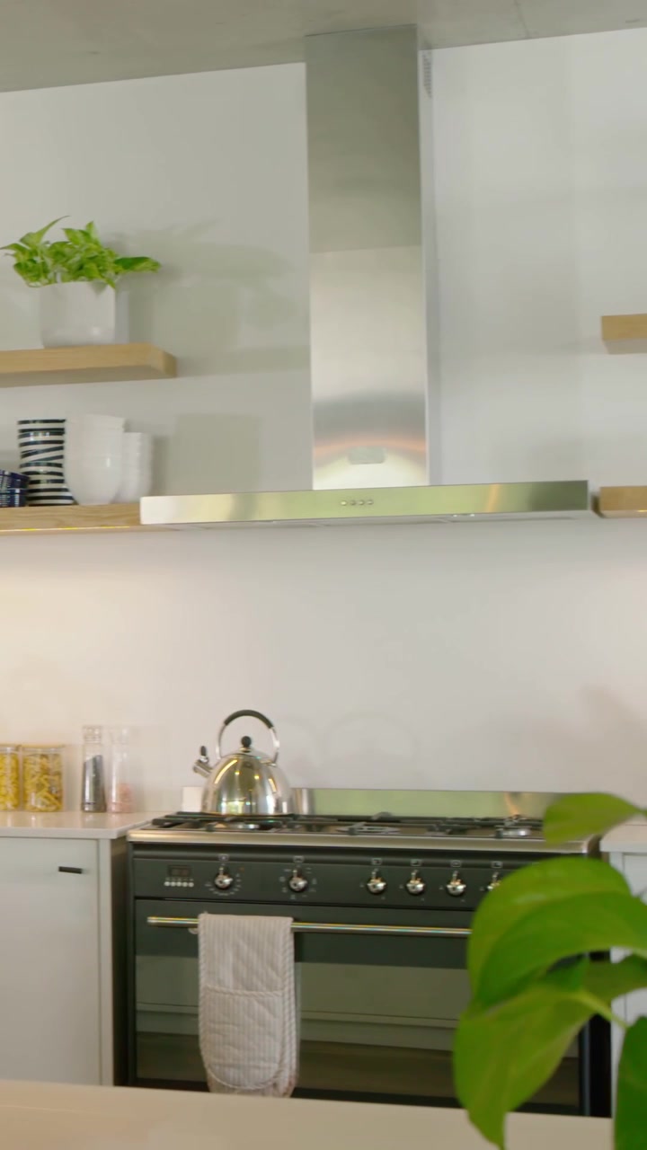 Video verticale: Inquadratura panoramica che parte da un lampadario a sospensione, rivelando una cucina a gas in acciaio e un bollitore per mostrare la cucina