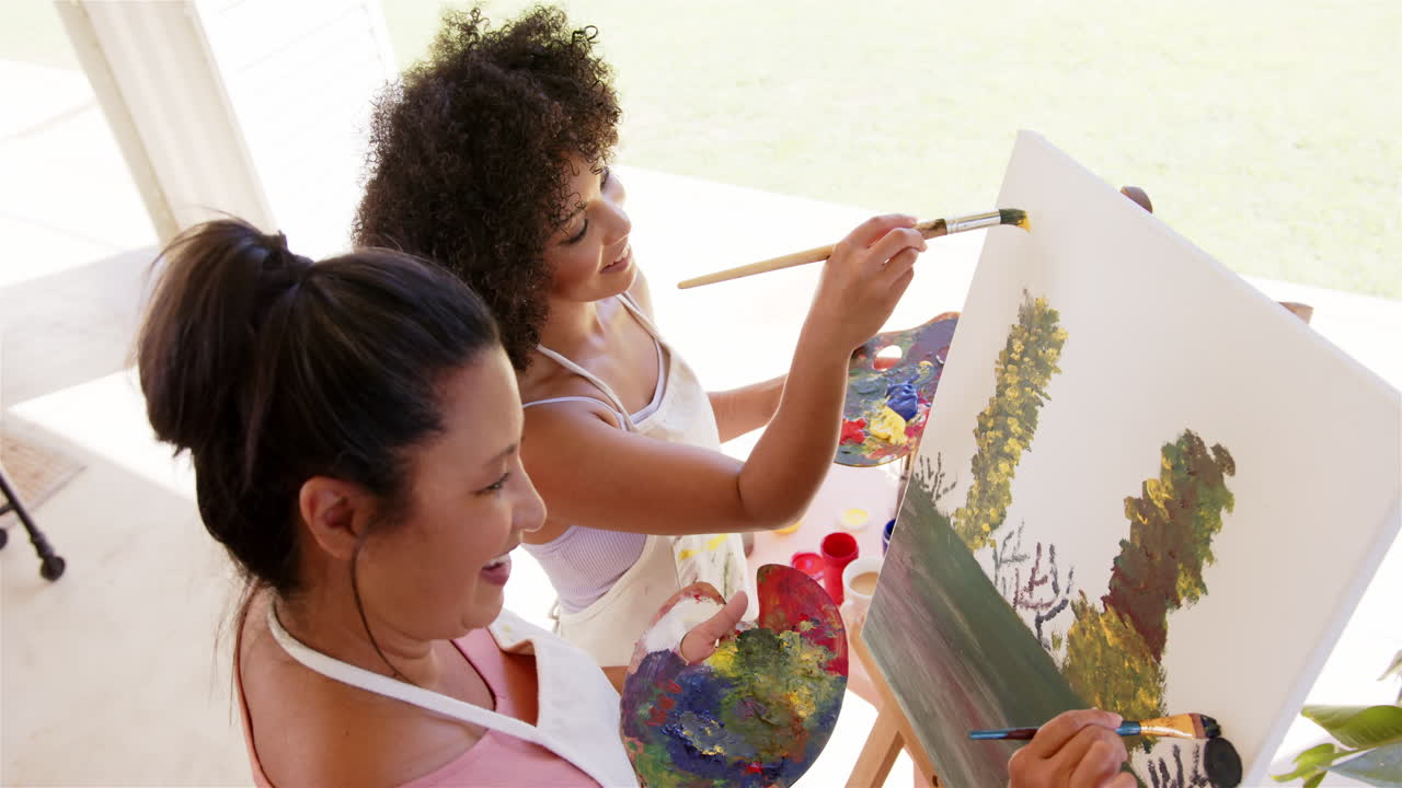Painting on canvas together, women enjoying creative activity outdoors