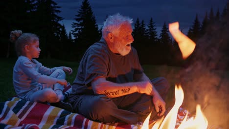 grandfather and grandchild enjoying a campfire at dusk