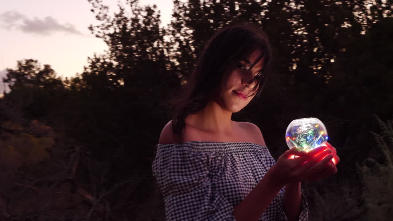 An alluring mysterious girl on a quest with a magic crystal orb glowing in an enchanted fantasy land