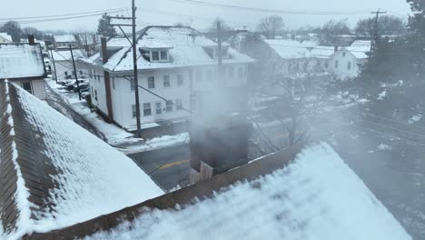 Rising-fumes-of-smokestack-on-snowy-rooftop-of-house-in-neighborhood