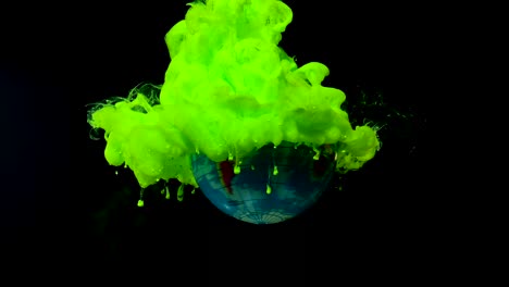 planet earth from space is spinning around its axis. green watercolor ink in water on a black background.