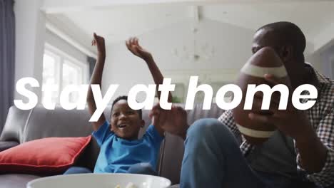 Animation-of-stay-at-home-text-over-african-american-father-and-son-watching-tv