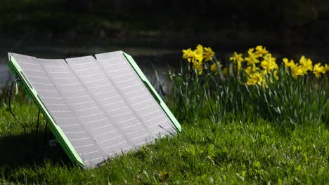 Das-Faltbare-Solarpanel-Set-Erzeugt-Strom-An-Einem-Sonnigen-Tag-Mit-Blumen-Im-Hintergrund