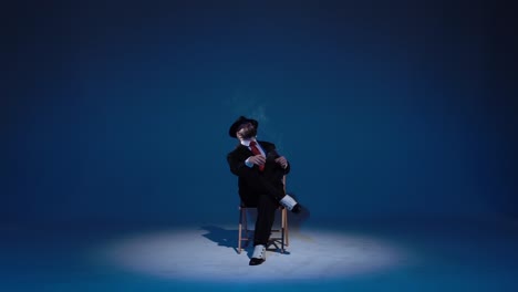 man in suit performing on a blue stage with spotlight