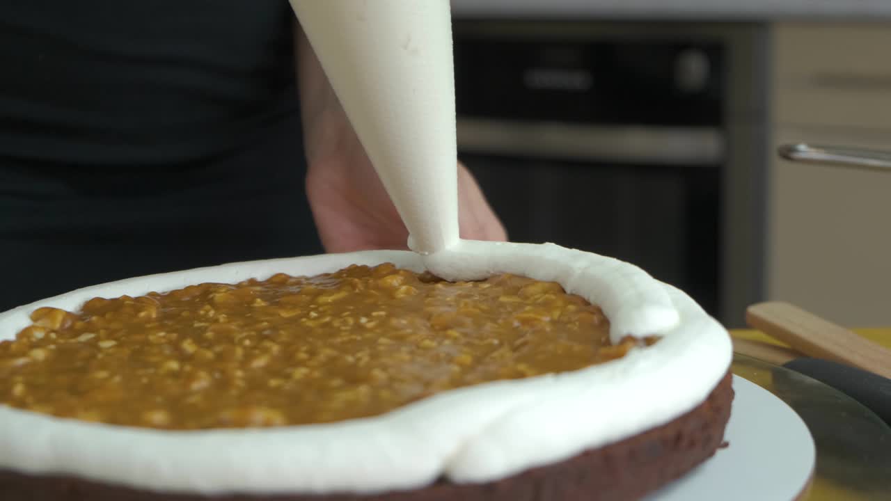 cerca de las manos de la mujer haciendo pastel dulce con crema blanca y galleta.